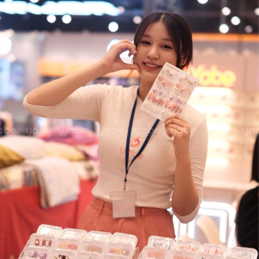 Why Choose Yabe as Your Leading Handmade Press-on Nail Distributor? 8 A woman holding a phone and a display of nail polish